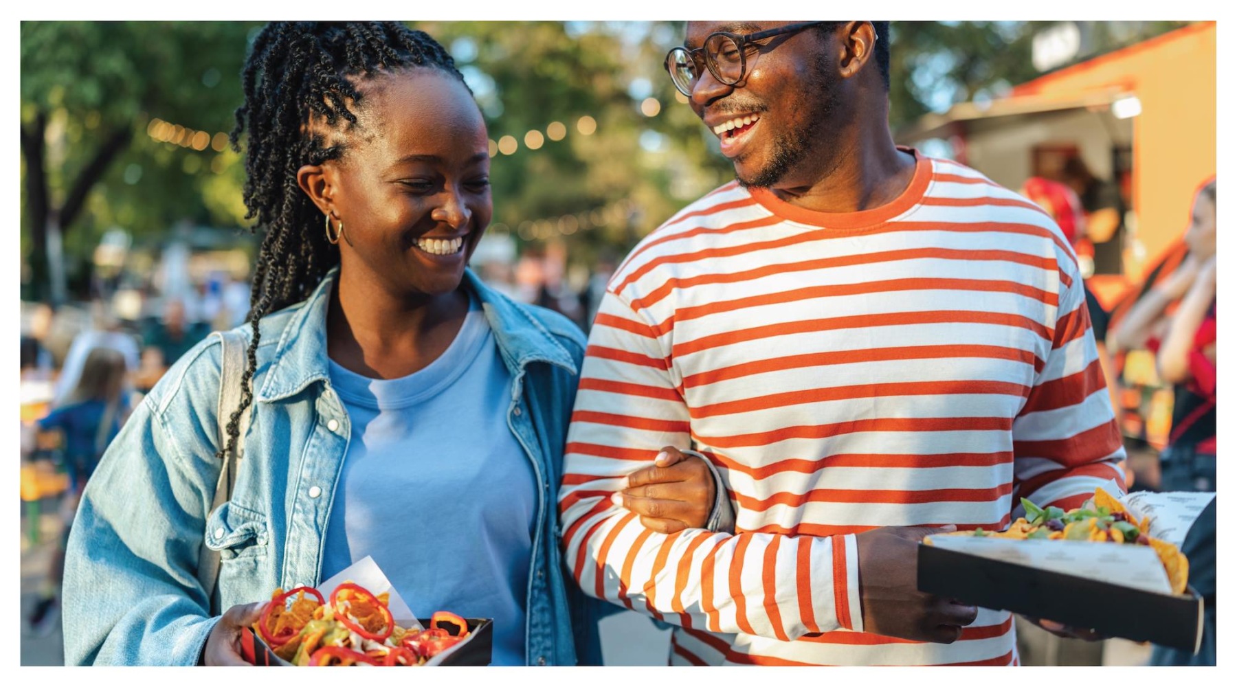 a couple walking and smiling while holding food